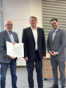Bürgermeister Norbert Holtermann (lk.) freut sich über die Urkunde, die ihm vom Landrat Marc-André Burgdorf (Mitte) und Roman Skrodzki von der Firma BREKO überreicht wurde. Fotoquelle: Landkreis Emsland