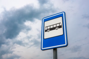 A low angle shot of a bus stop sign with a background of blue cloudy sky