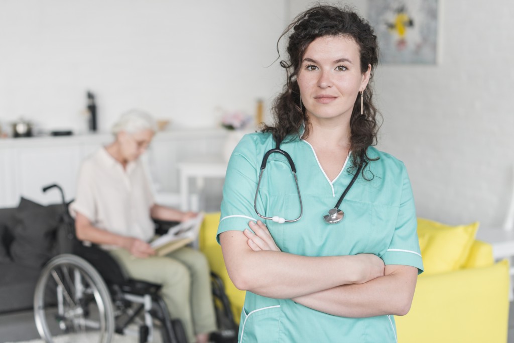 portrait-young-female-nurse-standing-front-senior-woman-sitting-wheel-chair