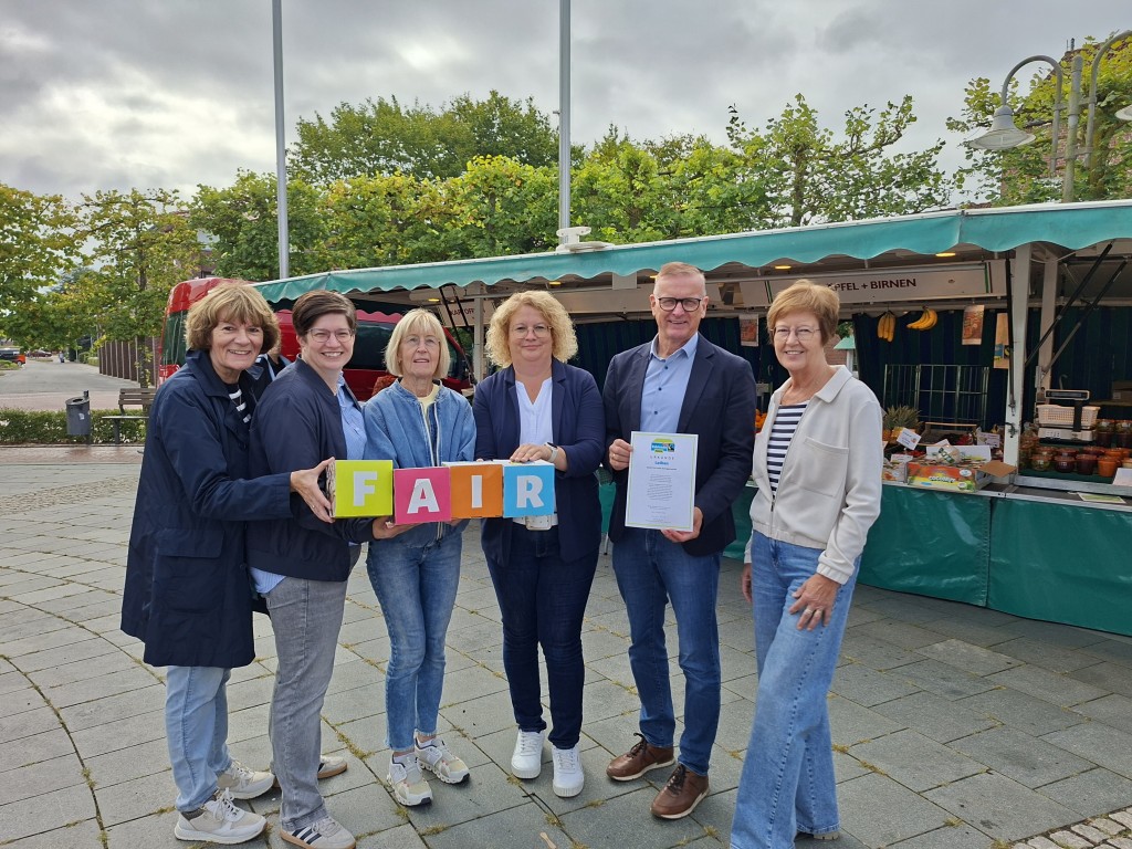 Samtgemeindebürgermeister Helmut Wilkens freut sich gemeinsam mit Mitgliedern des Teams „Faire Welt“ über die erneute Auszeichnung der Samtgemeinde Lathen als Fairtrade-Town. Im Bild (v. l. n. r.): Rita Schmeling, Andrea Schmees, Wilma Weber, Claudia Reinken, Samtgemeindebürgermeister Helmut Wilkens sowie Johanna Willenborg auf dem Wochenmarkt in Lathen.